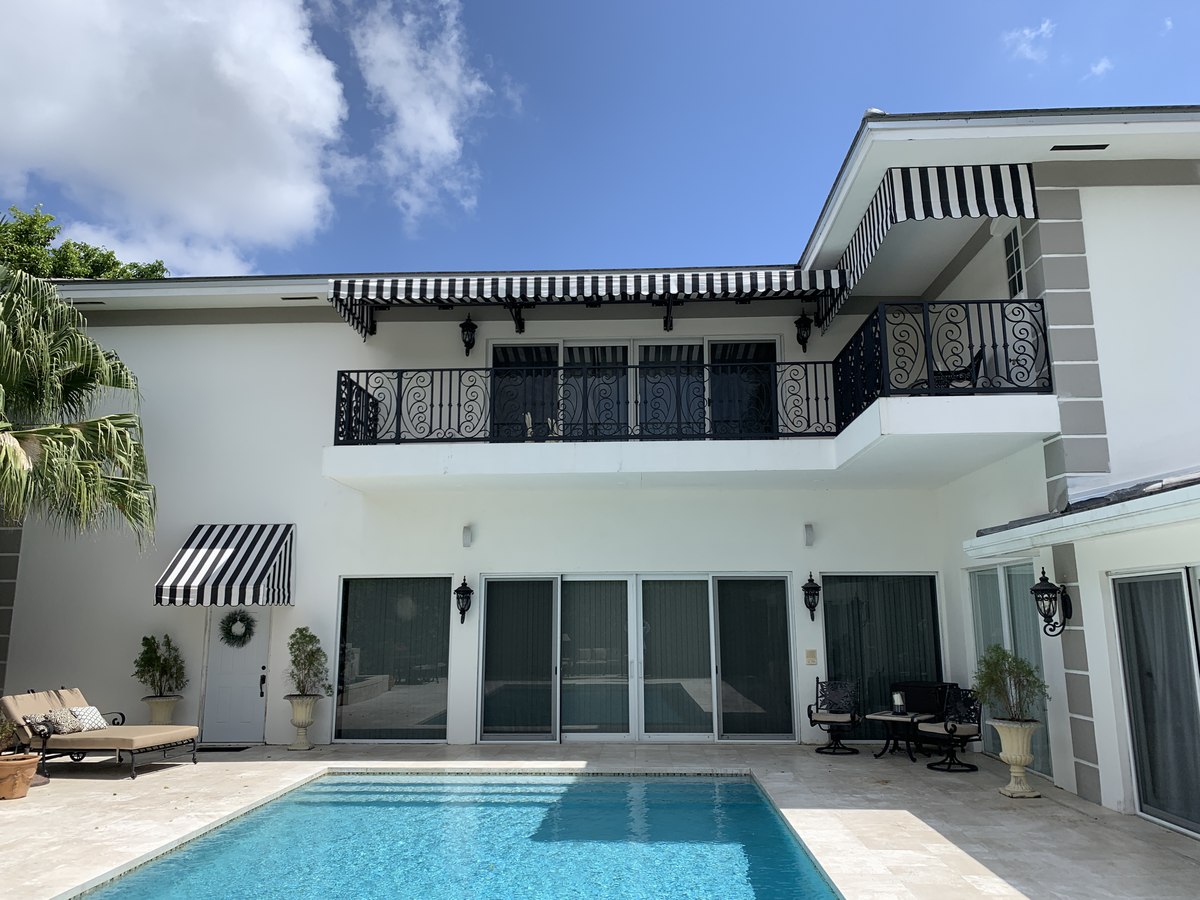 Striped window and terrace awnings beside a pool