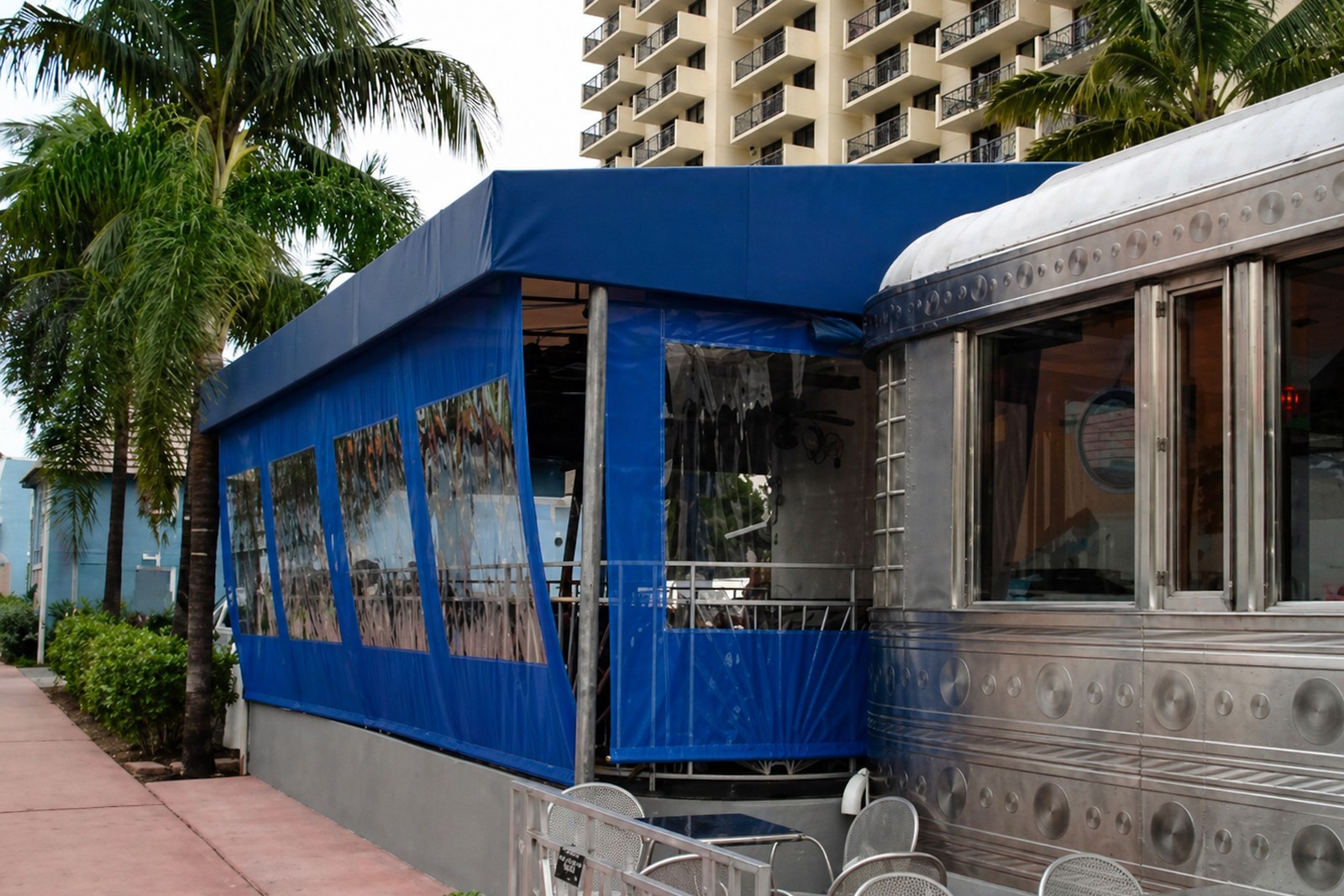 Blue canopy with clear side curtains beside a diner
